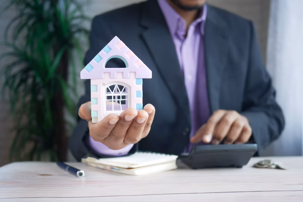 How much down payment do you need to buy a house, person holding house model and using a calculator