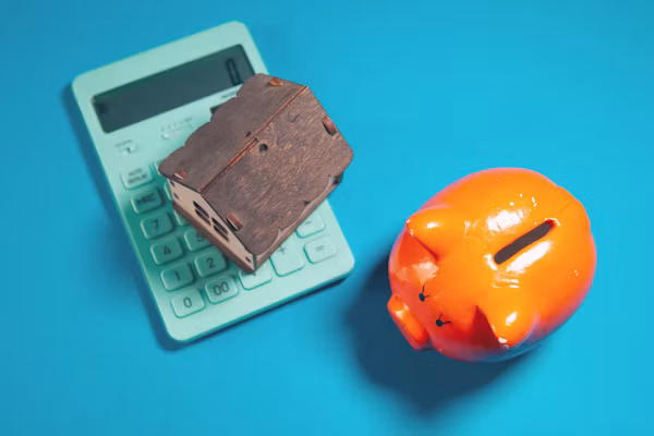 Fixed vs adjustable rate mortgage costs shown with a calculator, house model and piggy bank