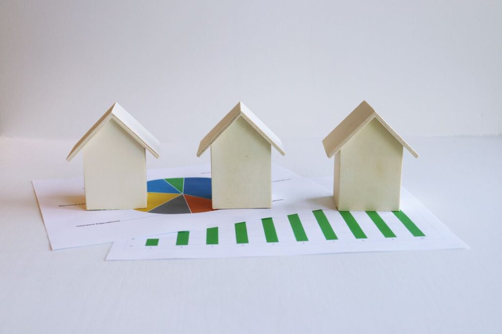 House models on financial charts comparing a mortgage recast vs refinance